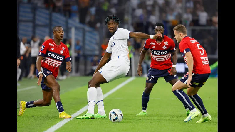 Cầu thủ của Lille chạy nhanh với bóng trước sự truy đuổi của cầu thủ Marseille. Cầu thủ của Lille chạy nhanh với bóng trước sự truy đuổi của cầu thủ Marseille.