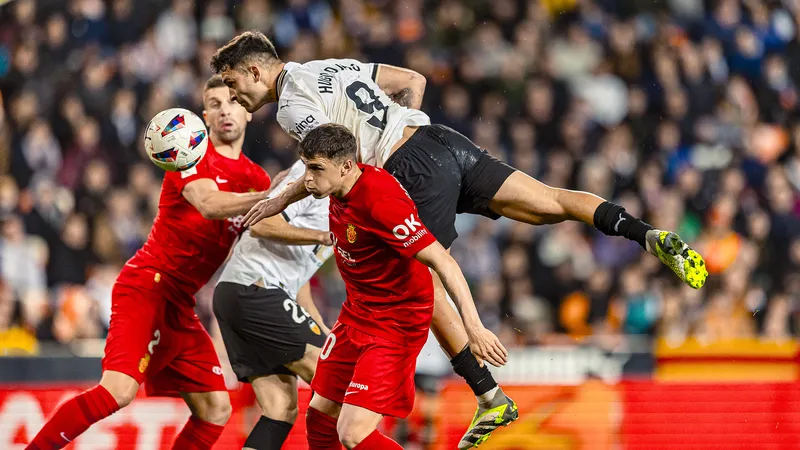 Cầu thủ của Valencia đi bóng vượt qua hậu vệ Mallorca trên sân cỏ